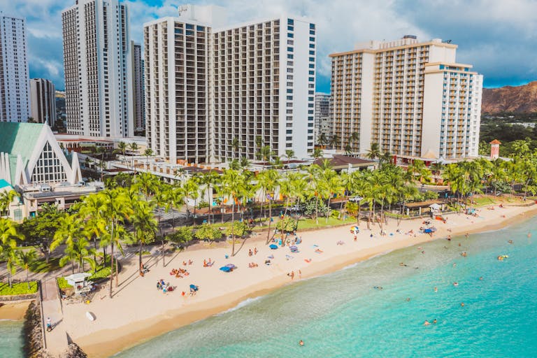 Beautiful aerial view of Waikiki beachfront with hotels and vibrant beachgoers enjoying the summer sun.