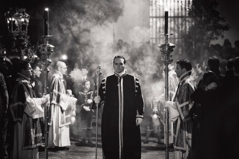 Black and white image capturing a traditional religious procession in Carmona, Spain.