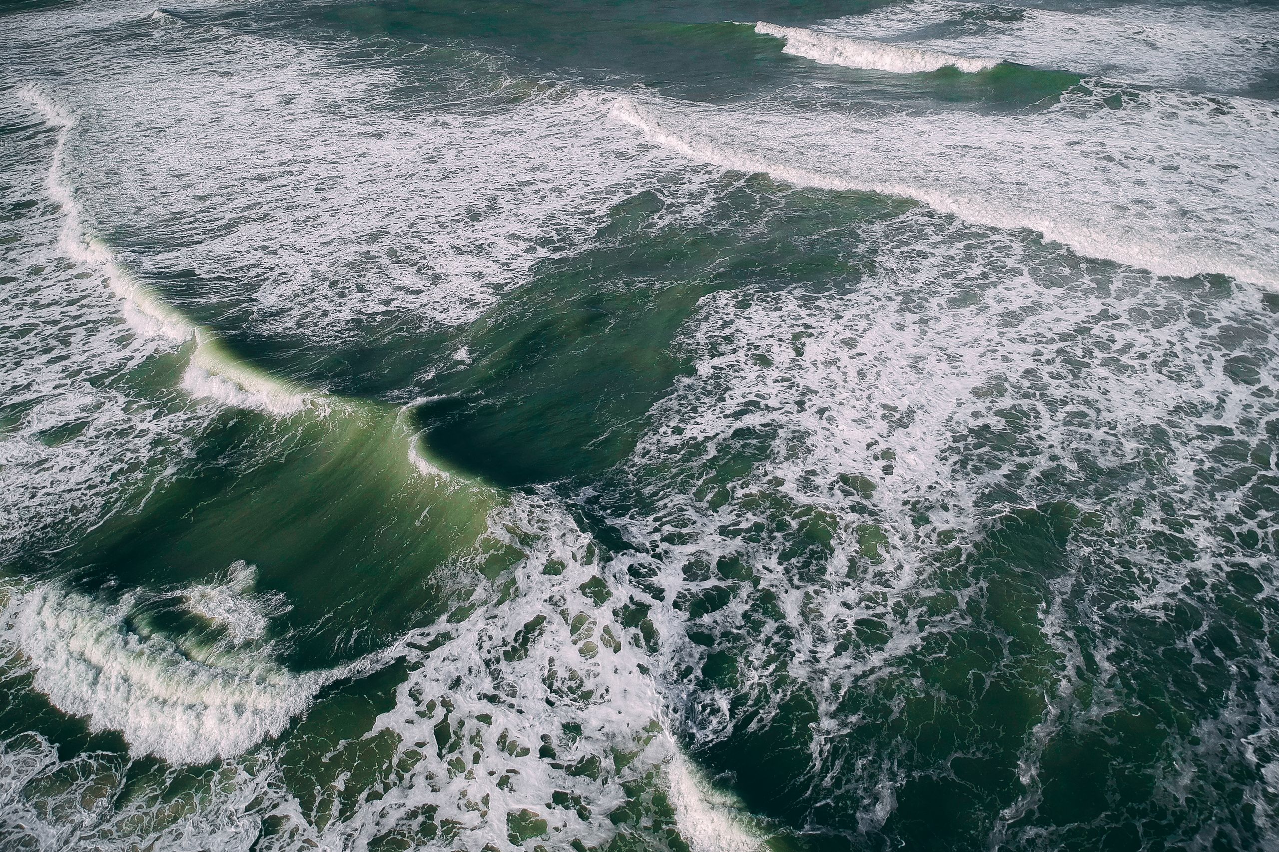Breathtaking aerial shot of ocean waves forming intricate patterns and textures.