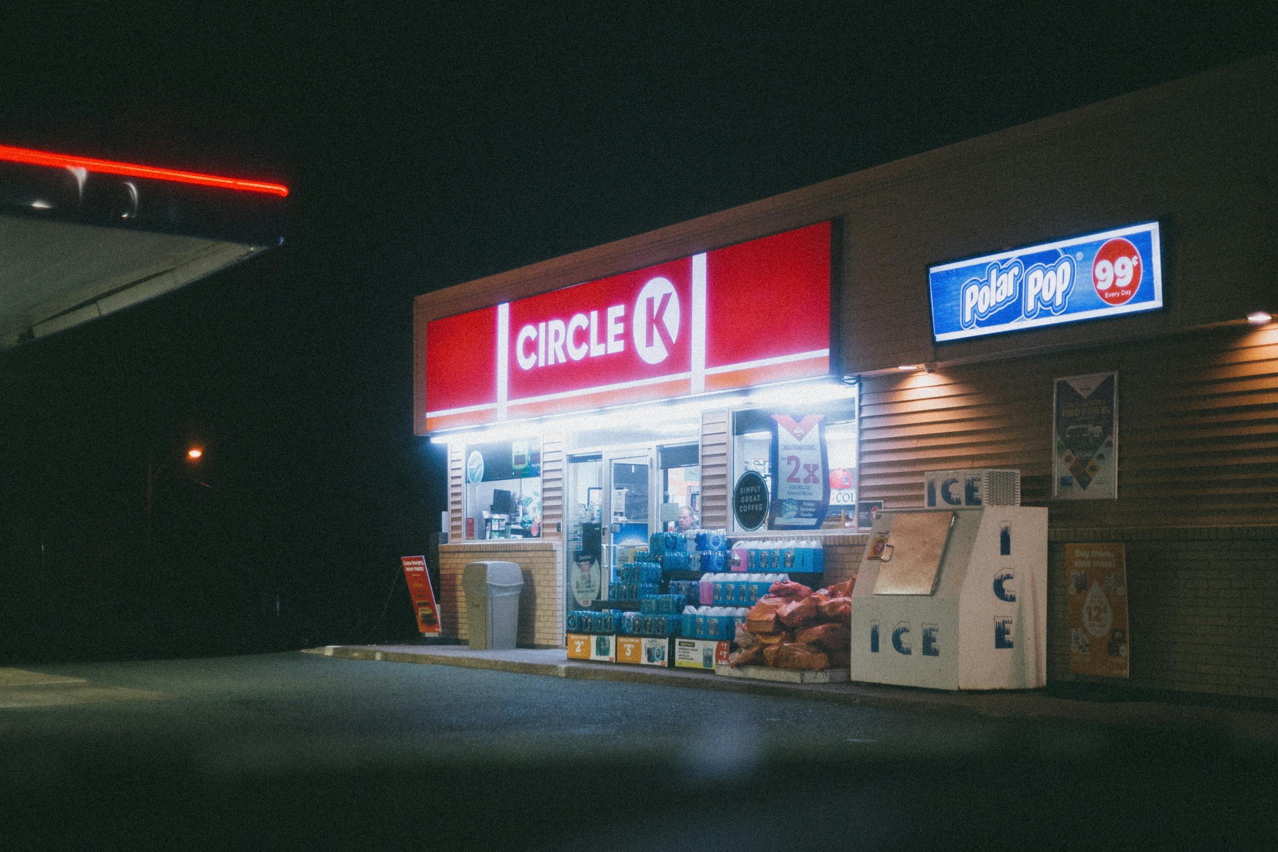 Brightly lit Circle K store at night with neon signage and outdoor ice machines.
