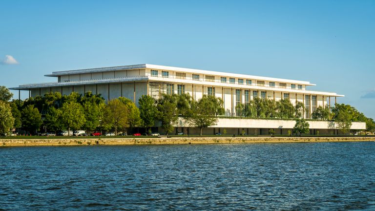 Captivating view of the Kennedy Center beside the Potomac River with lush greenery in summer.