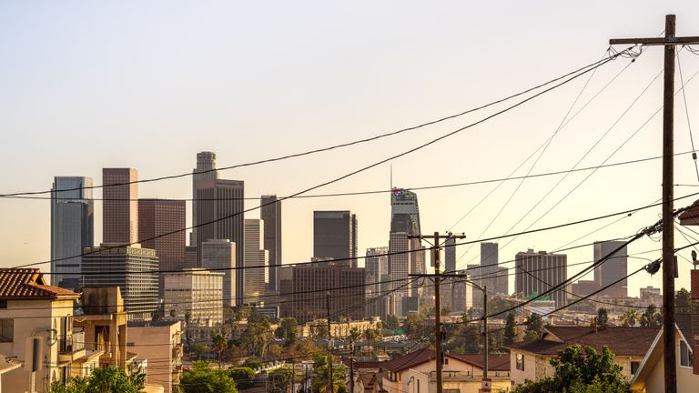 Capture of downtown Los Angeles skyline under a warm sunset, showcasing iconic skyscrapers and urban landscape.