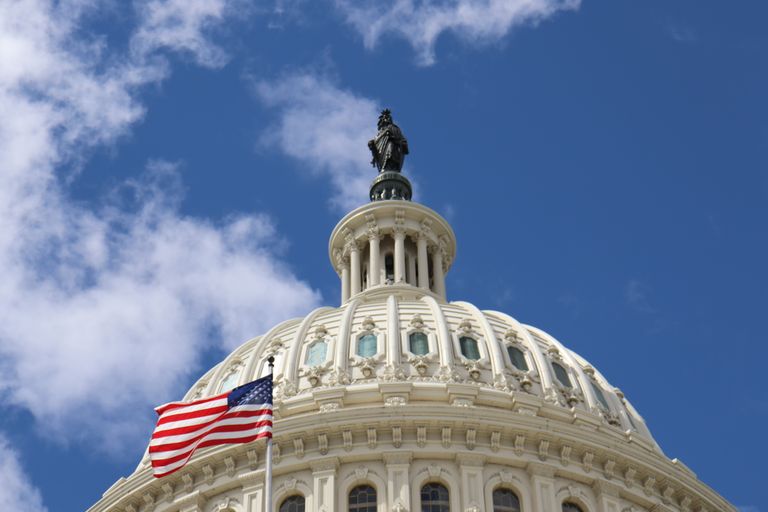 Capture of the U.S. Capitol dome with an American flag waving against a blue sky in Washington, D.C.
