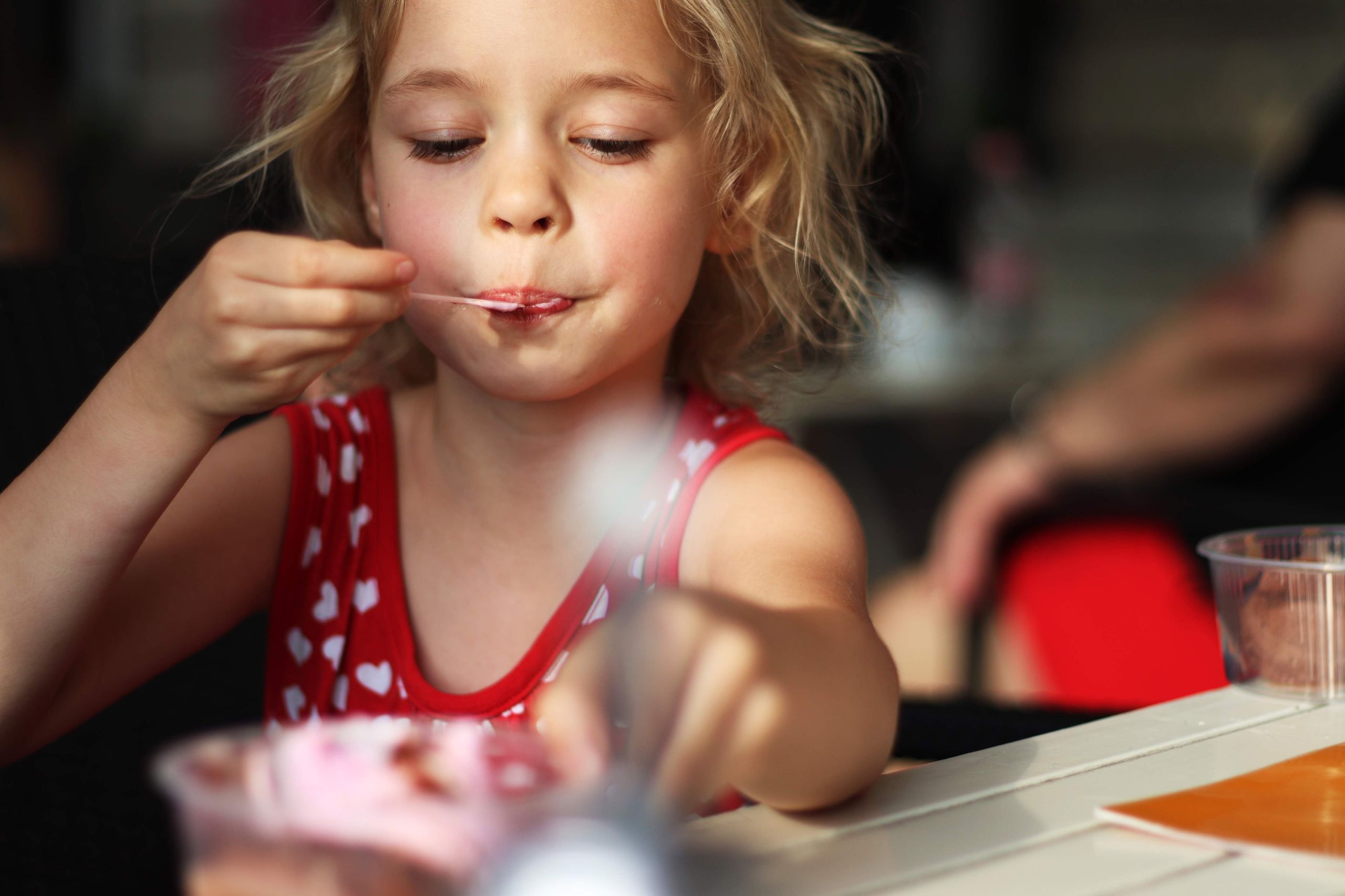 Charming girl eating tasty dessert while spending time in cafe and looking down