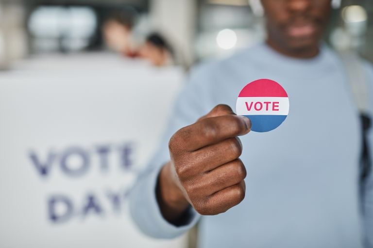 Close-up image of a person holding a vote sticker, symbolizing participation and civic duty.