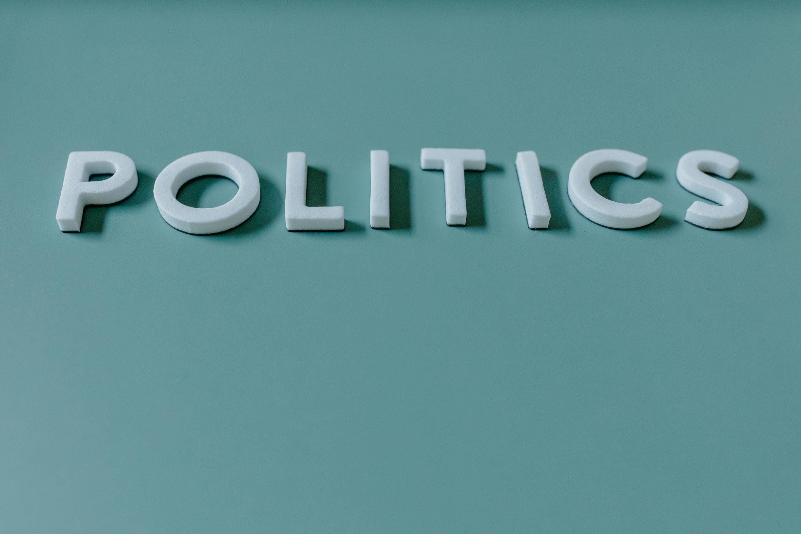 Close-up image of the word 'Politics' against a teal green background, highlighting political themes.