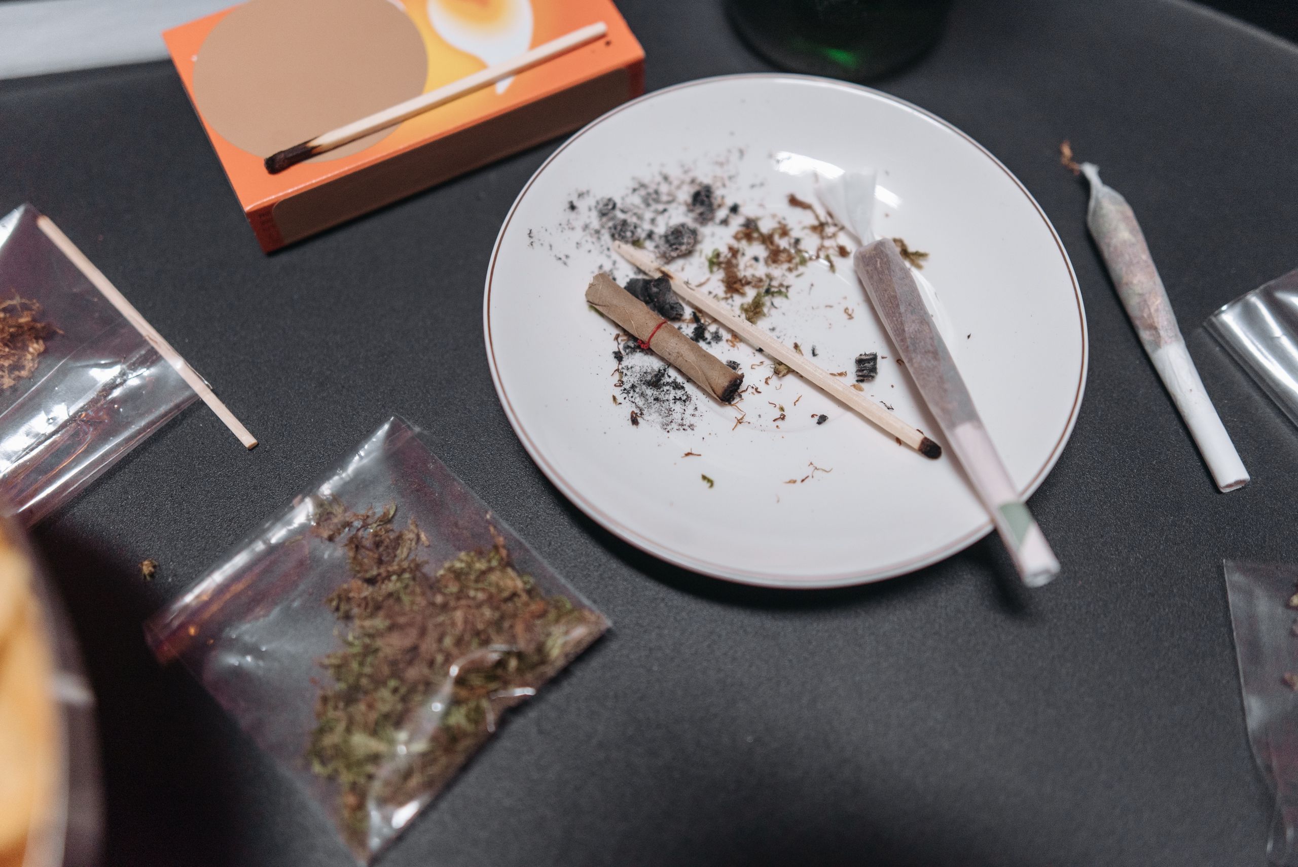 Close-up image showing cannabis paraphernalia, including joints and rolling paper on a table.