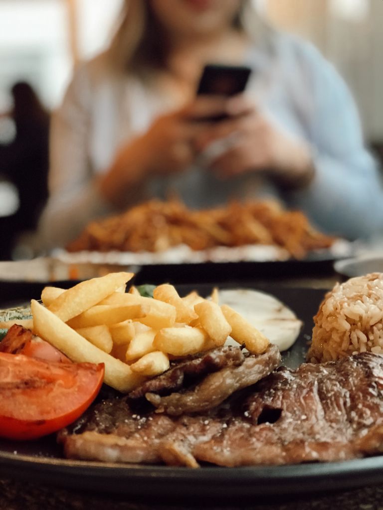Close-up of a delicious steak meal with fries, rice, and tomato, perfect for food enthusiasts.