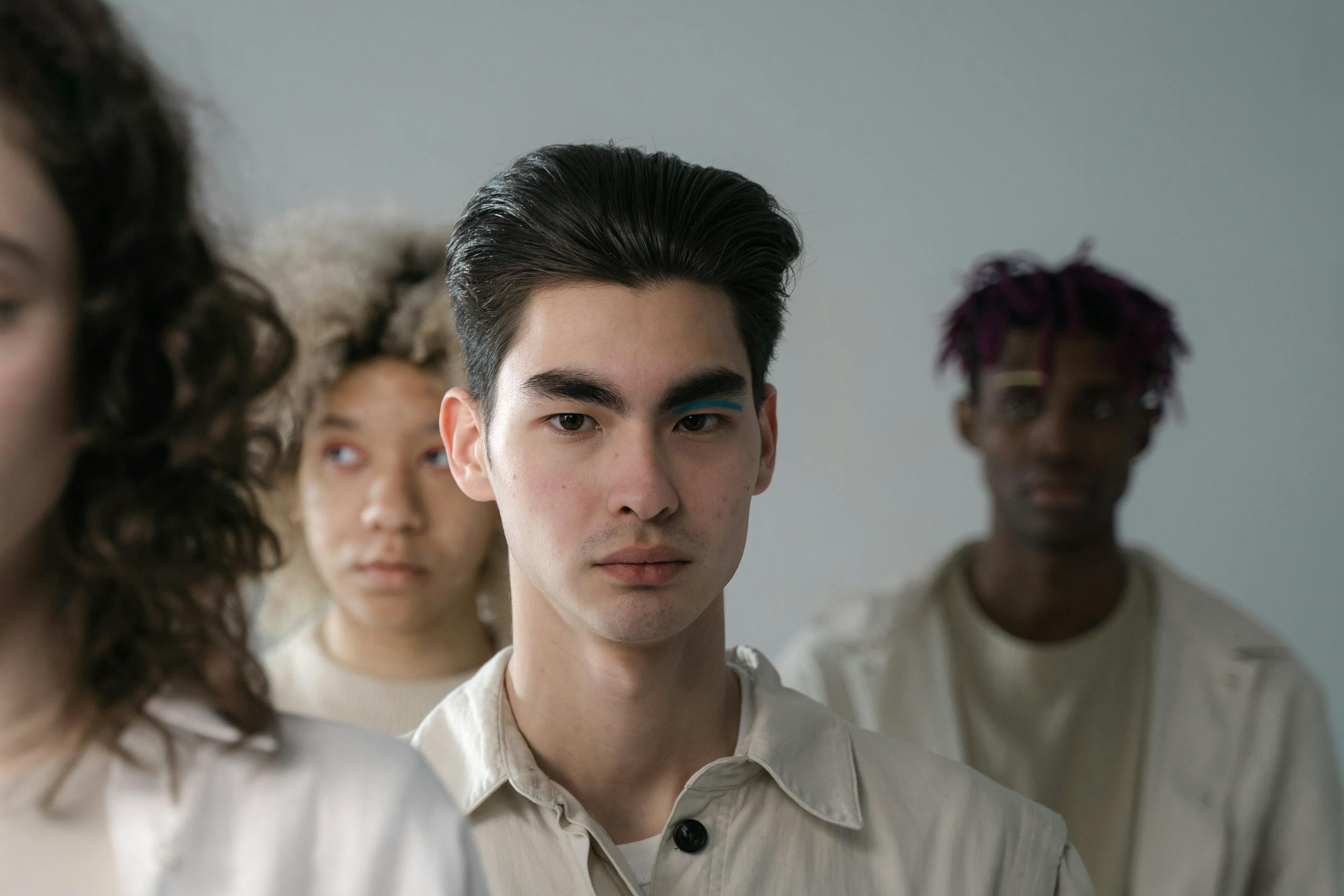 Close-up of a diverse group of young adults in neutral attire, emphasizing diversity and unity.
