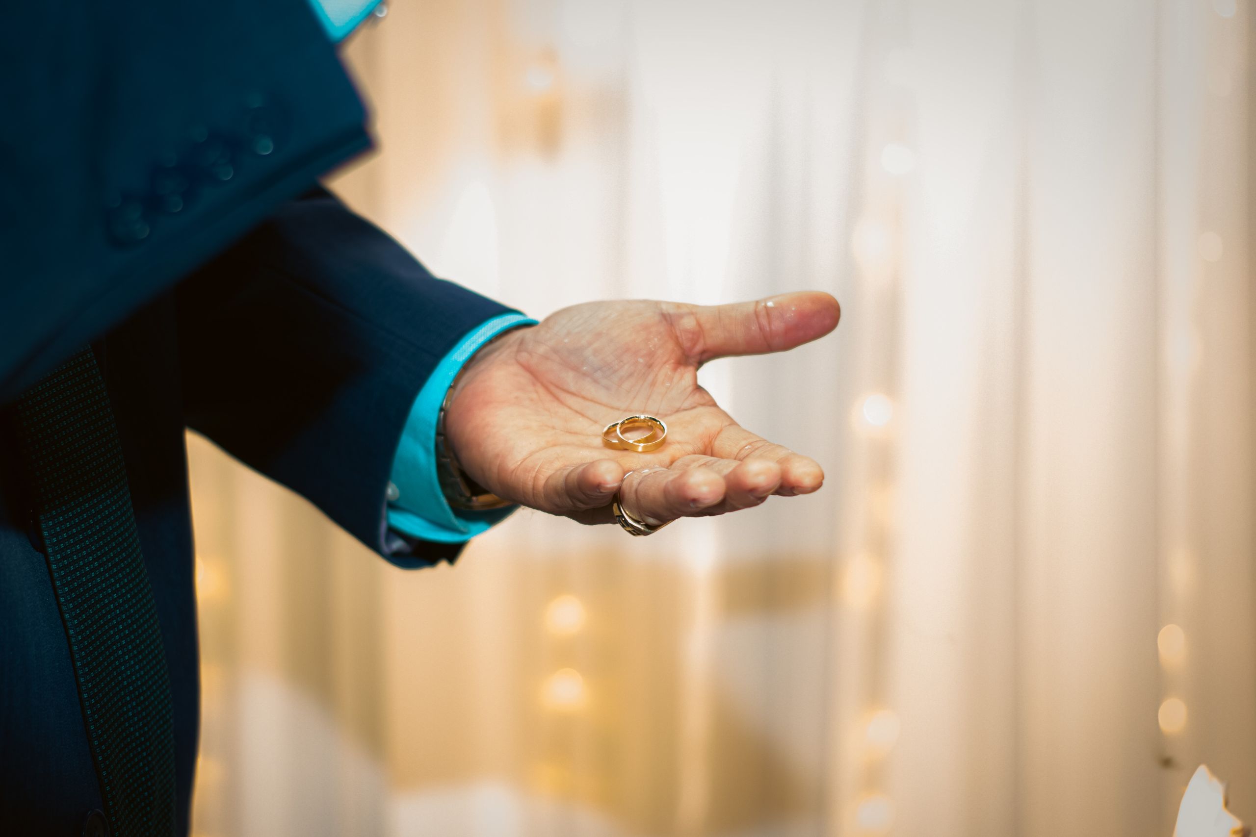 Close-up of a hand holding wedding rings, symbolizing marriage and commitment.