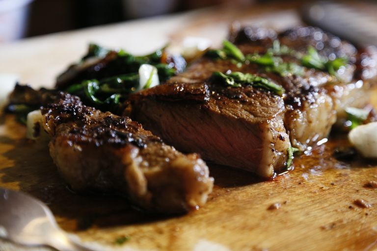 Close-up of a perfectly cooked steak garnished with fresh herbs on a cutting board.