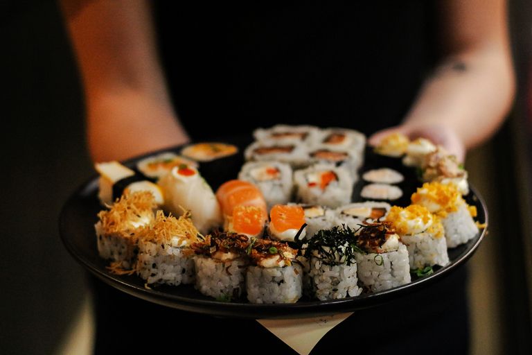 Close-up of a variety of delicious sushi rolls on a black plate, showcasing vibrant ingredients.