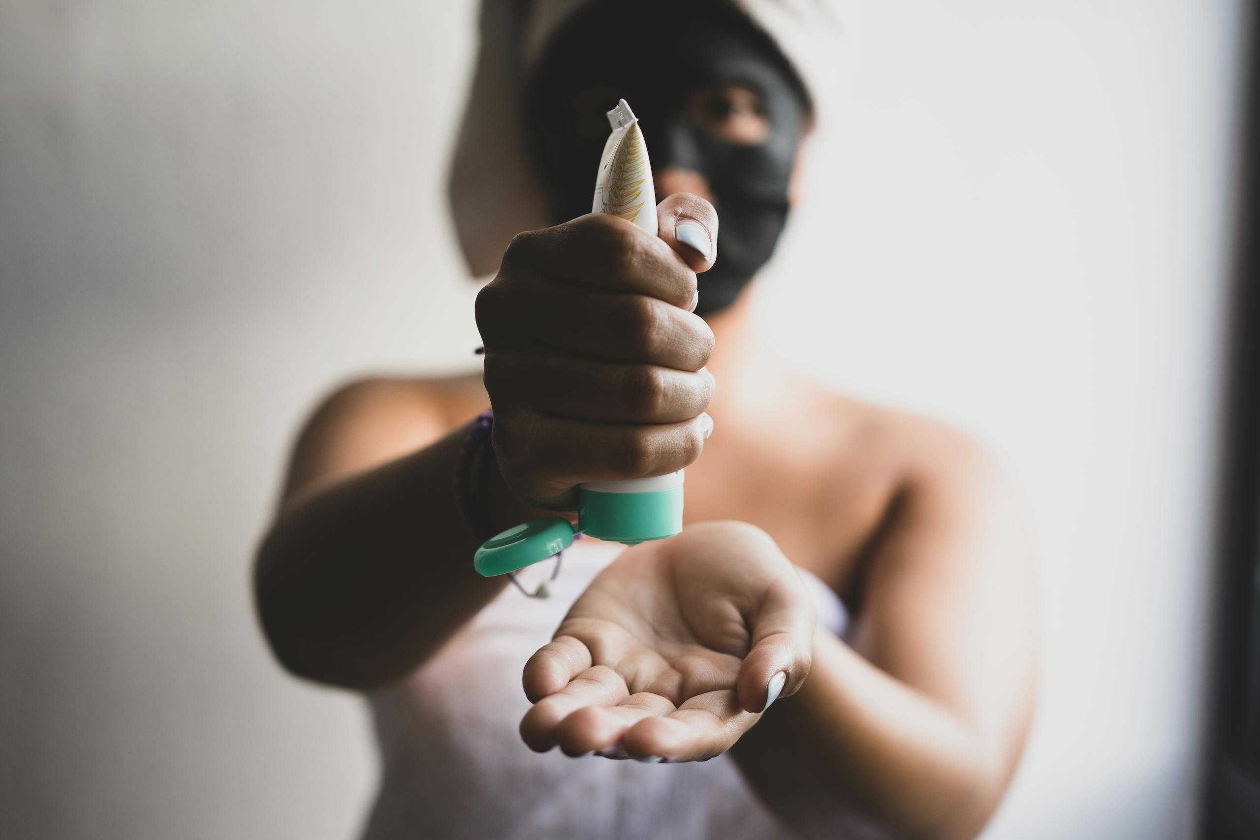 Close-up of a woman applying skincare cream with a blurred background, emphasizing a beauty routine.