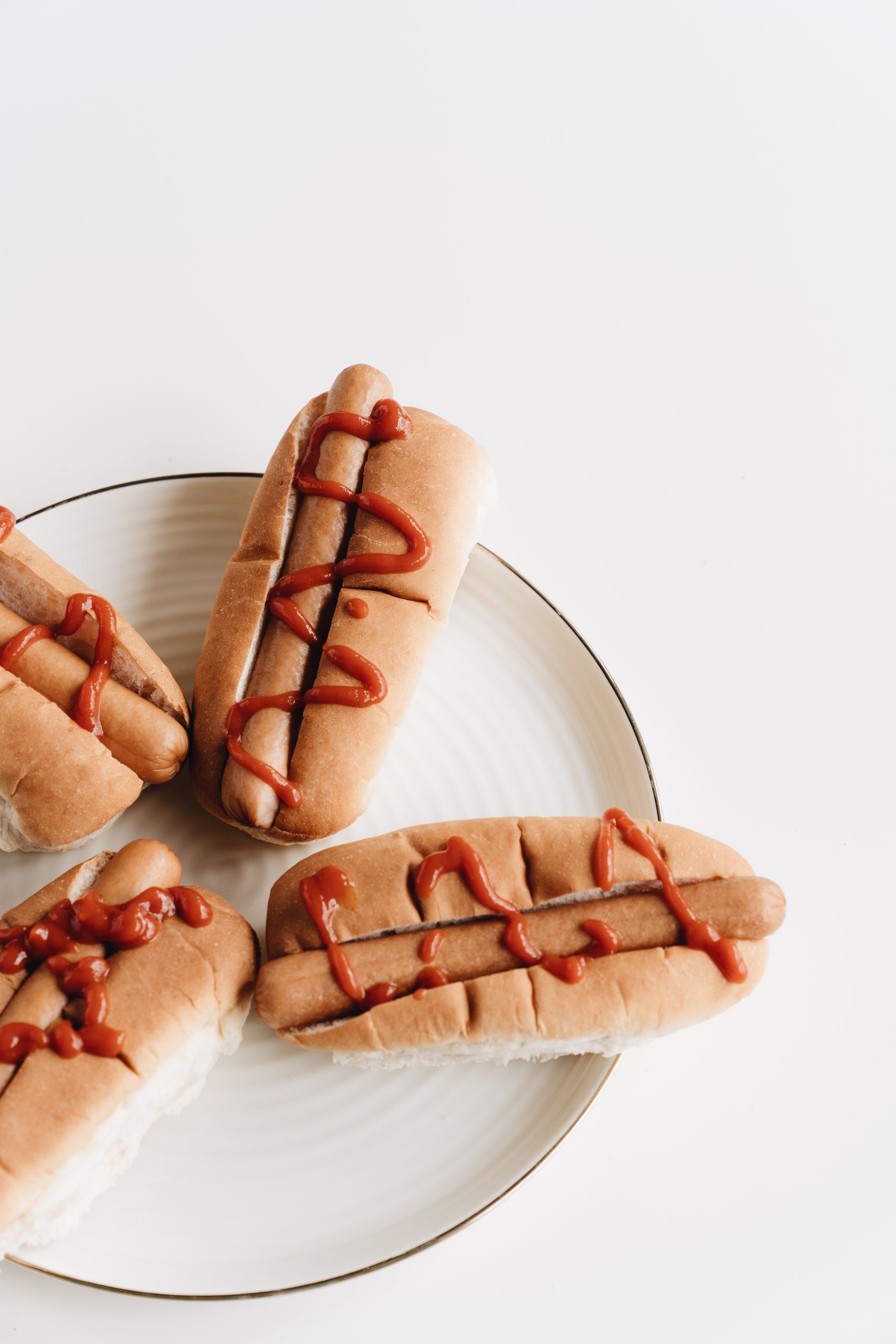 Close-up of hotdogs with ketchup drizzled on a white plate. Perfect tasty snack.