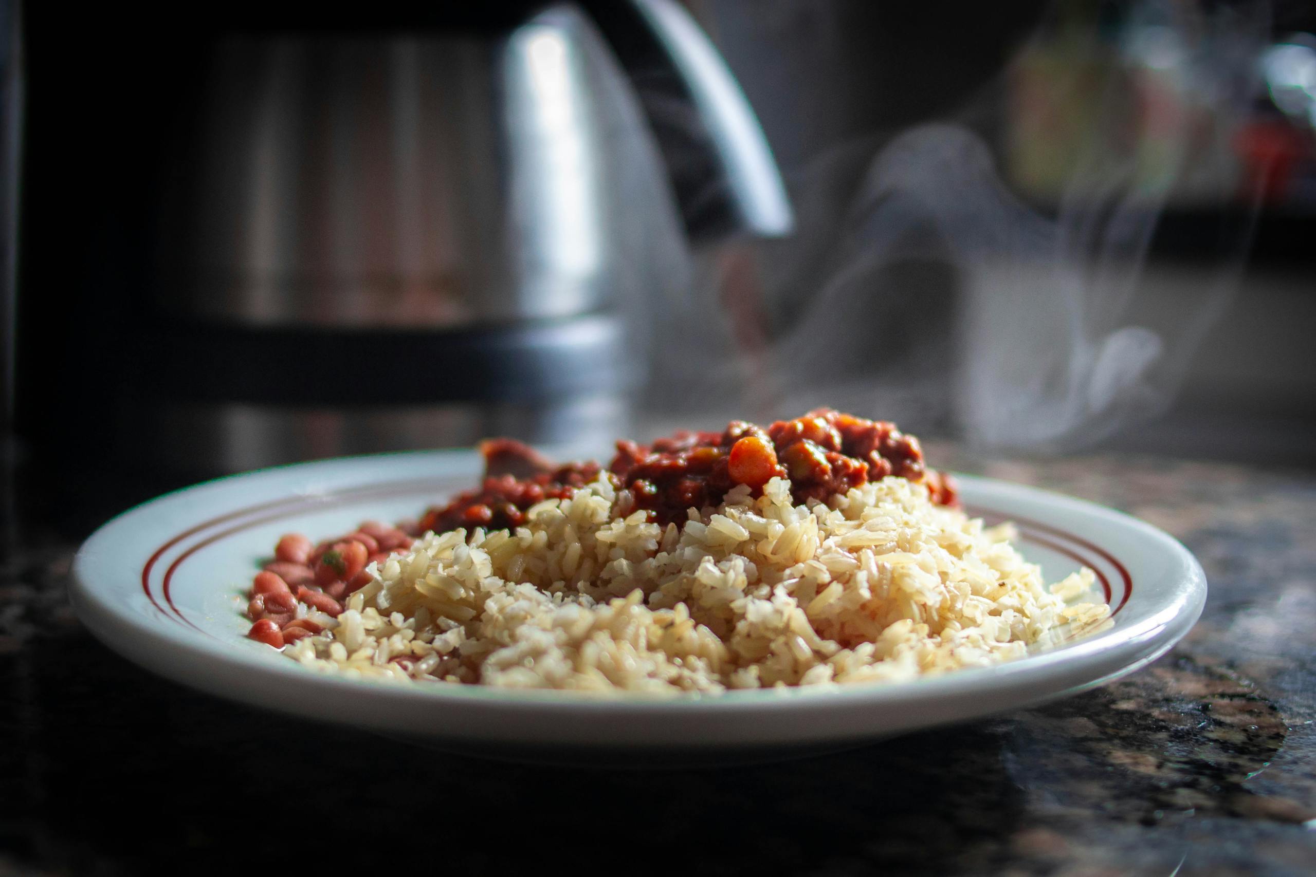 Close-up of steaming rice with chili beans on a plate, showcasing savory food.