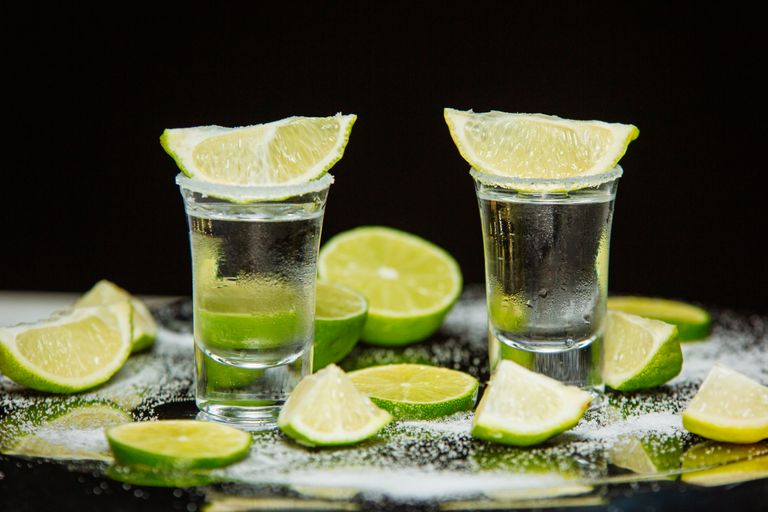 Close-up of tequila shots with lime slices and salt, creating a tropical vibe.