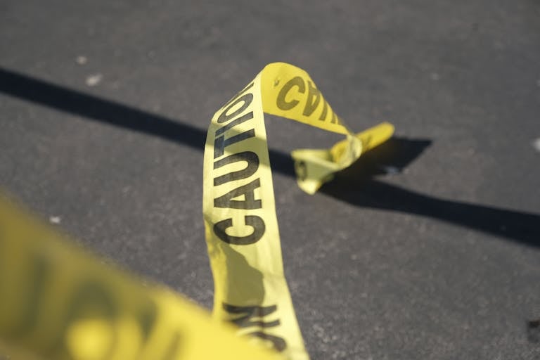 Close-up of yellow caution tape on pavement, suggesting danger or warning.