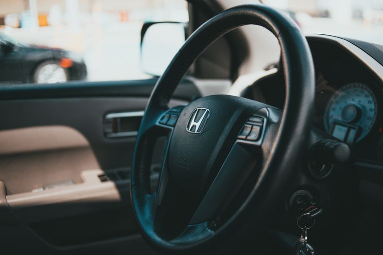 A close-up shot of a car steering wheel with dashboard, showcasing vehicle interior details.