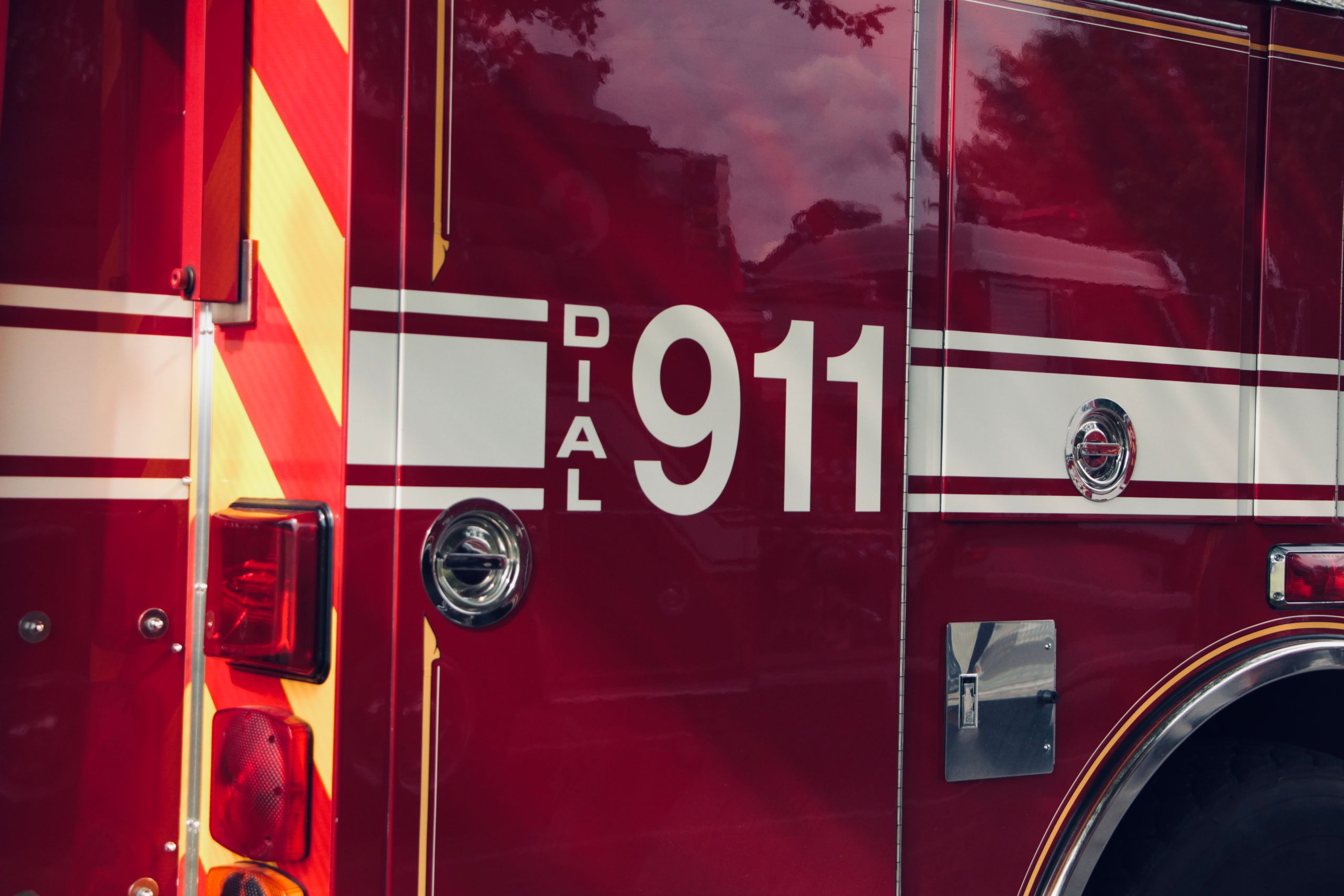 Close-up shot of a firetruck's door featuring the 911 emergency number.