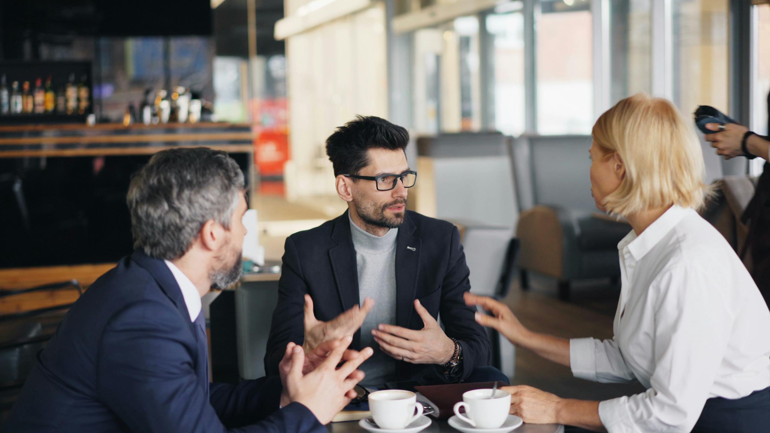 Colleagues having a strategic discussion over coffee in a stylish caf&eacute;.