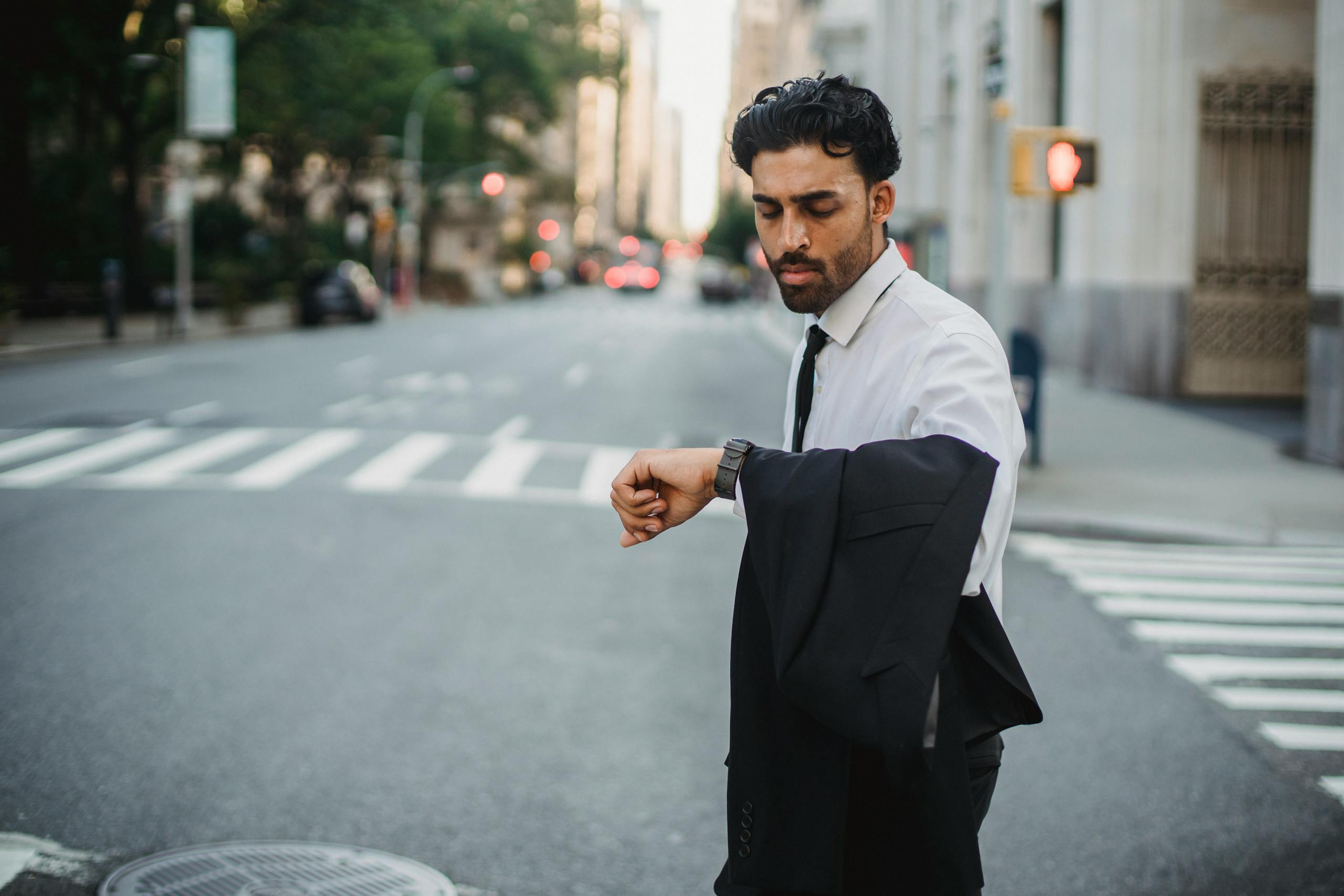 Confident young businessman checking his watch while standing on an urban street.