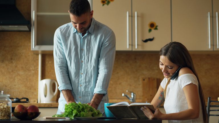 Couple preparing food and enjoying time in their stylish modern kitchen.