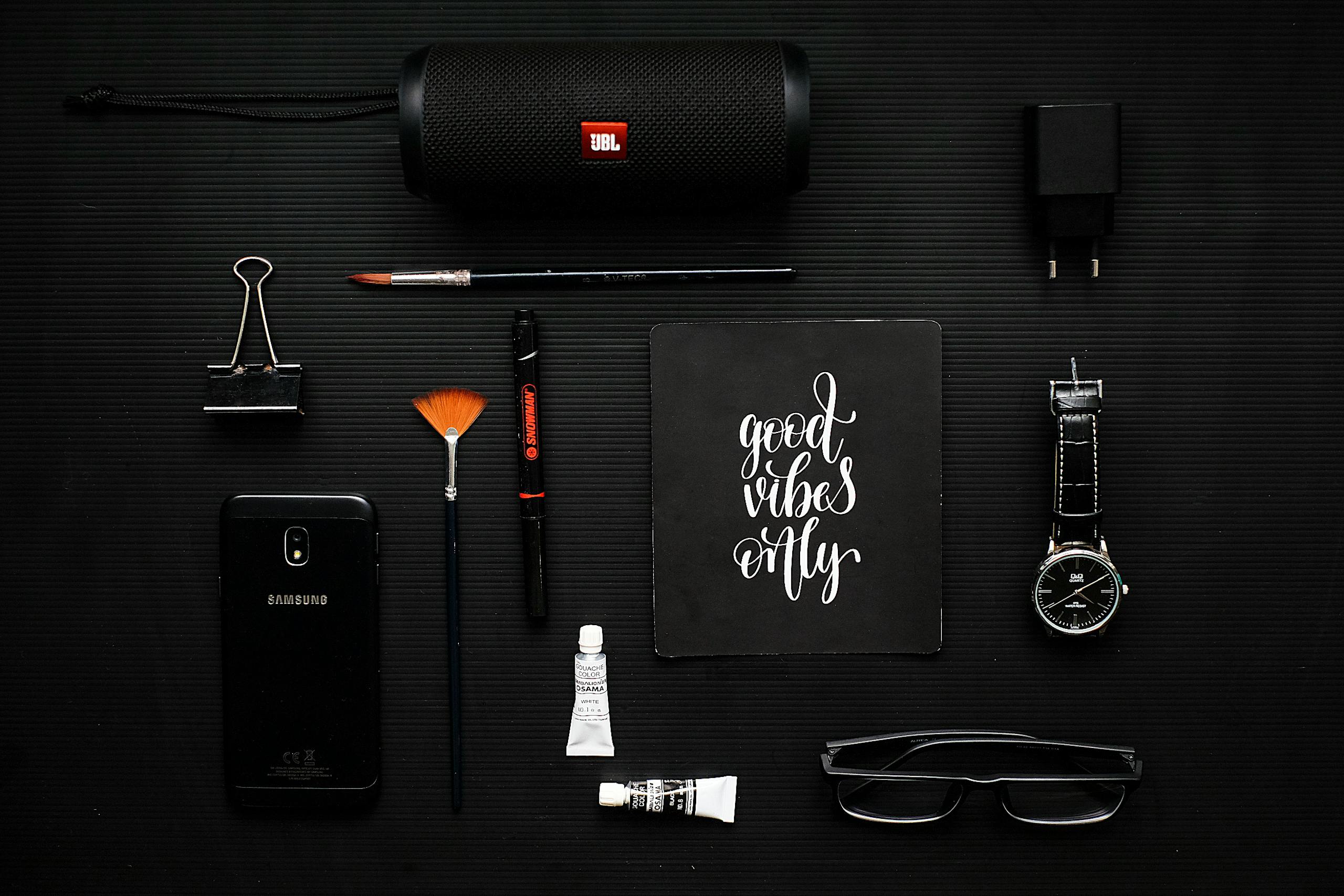Creative flat lay of modern gadgets and art supplies on a dark surface, conveying a mood of style and inspiration.