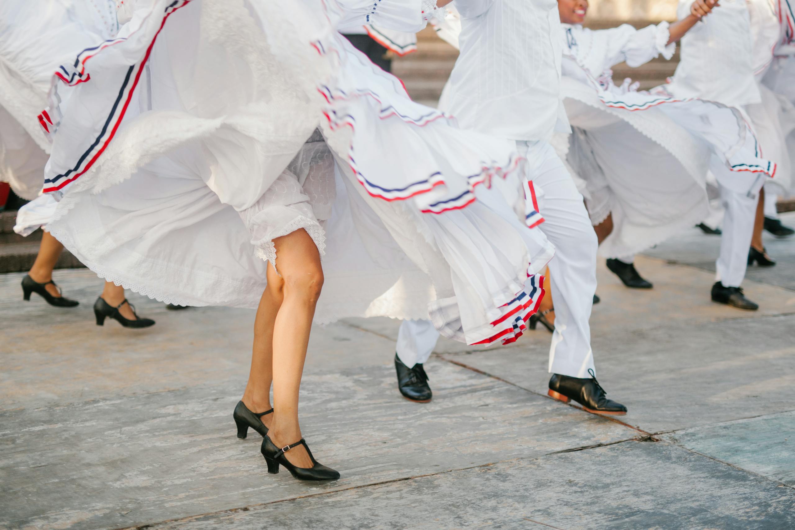 Crop unrecognizable artists in white costumes dancing on street during festival on sunny day