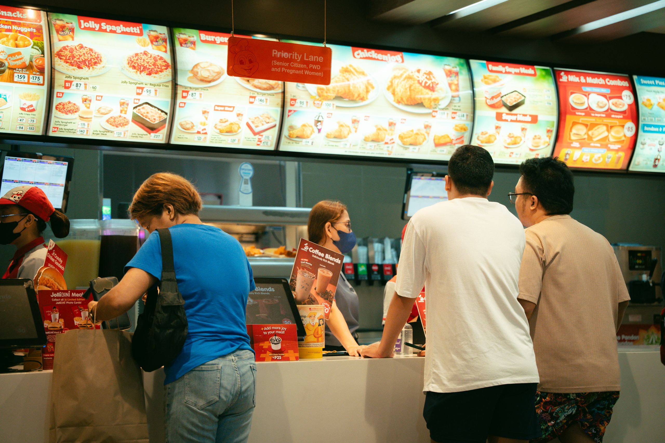 Customers ordering food at a fast food restaurant counter. Busy atmosphere.