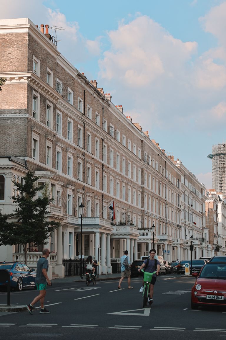 Cyclists and pedestrians in front of iconic Victorian townhouses in South Kensington, London.
