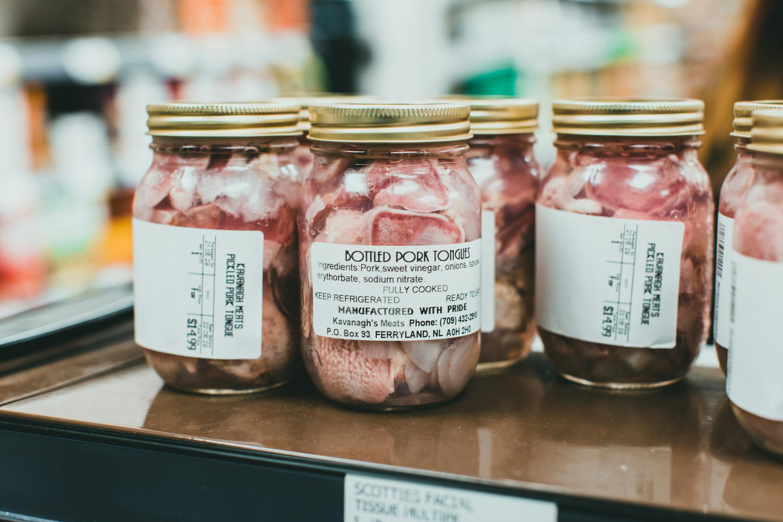 Detailed close-up shot of bottled pork tongues on display in a supermarket.