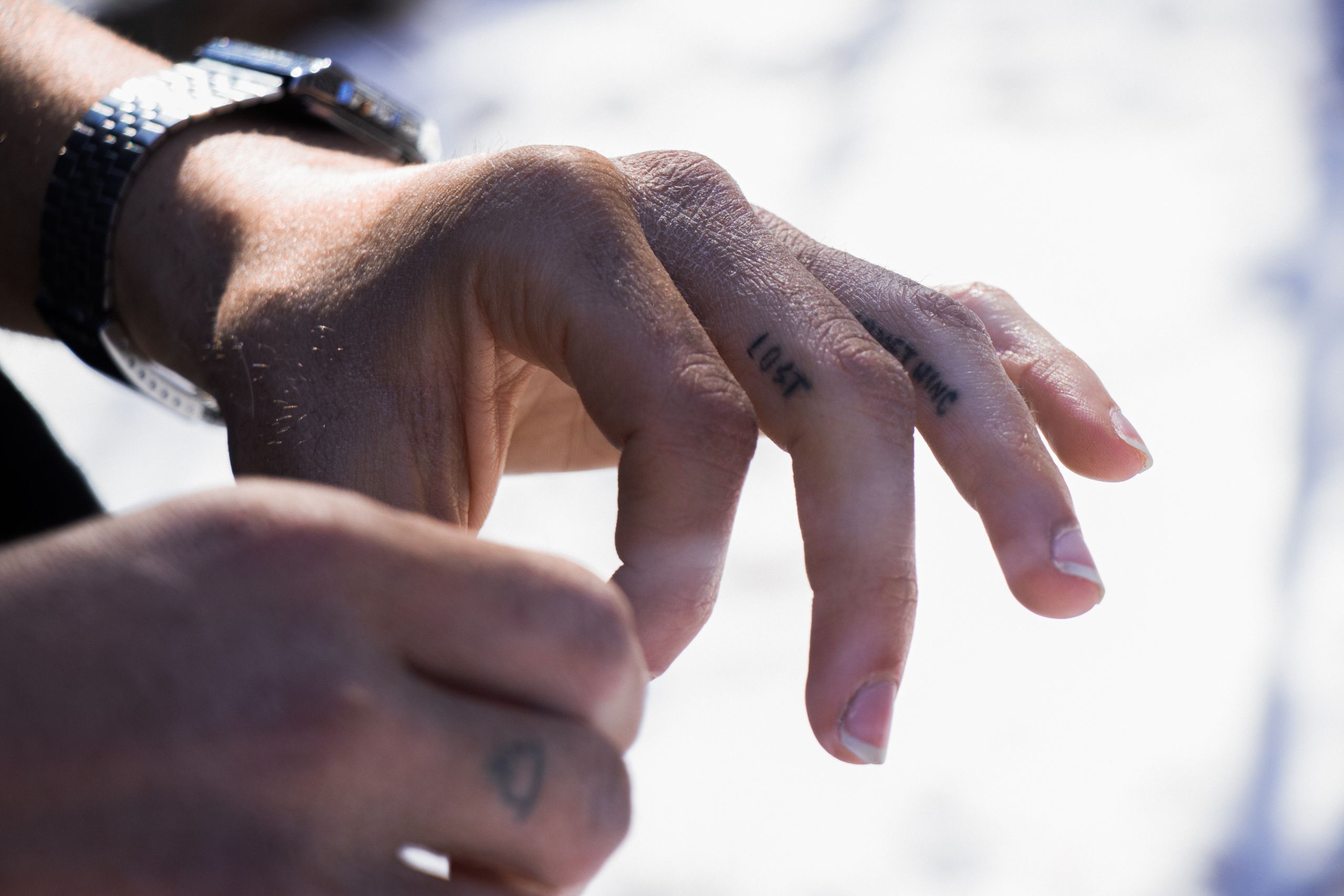 Detailed view of tattooed fingers in natural light highlighting skin texture and design.