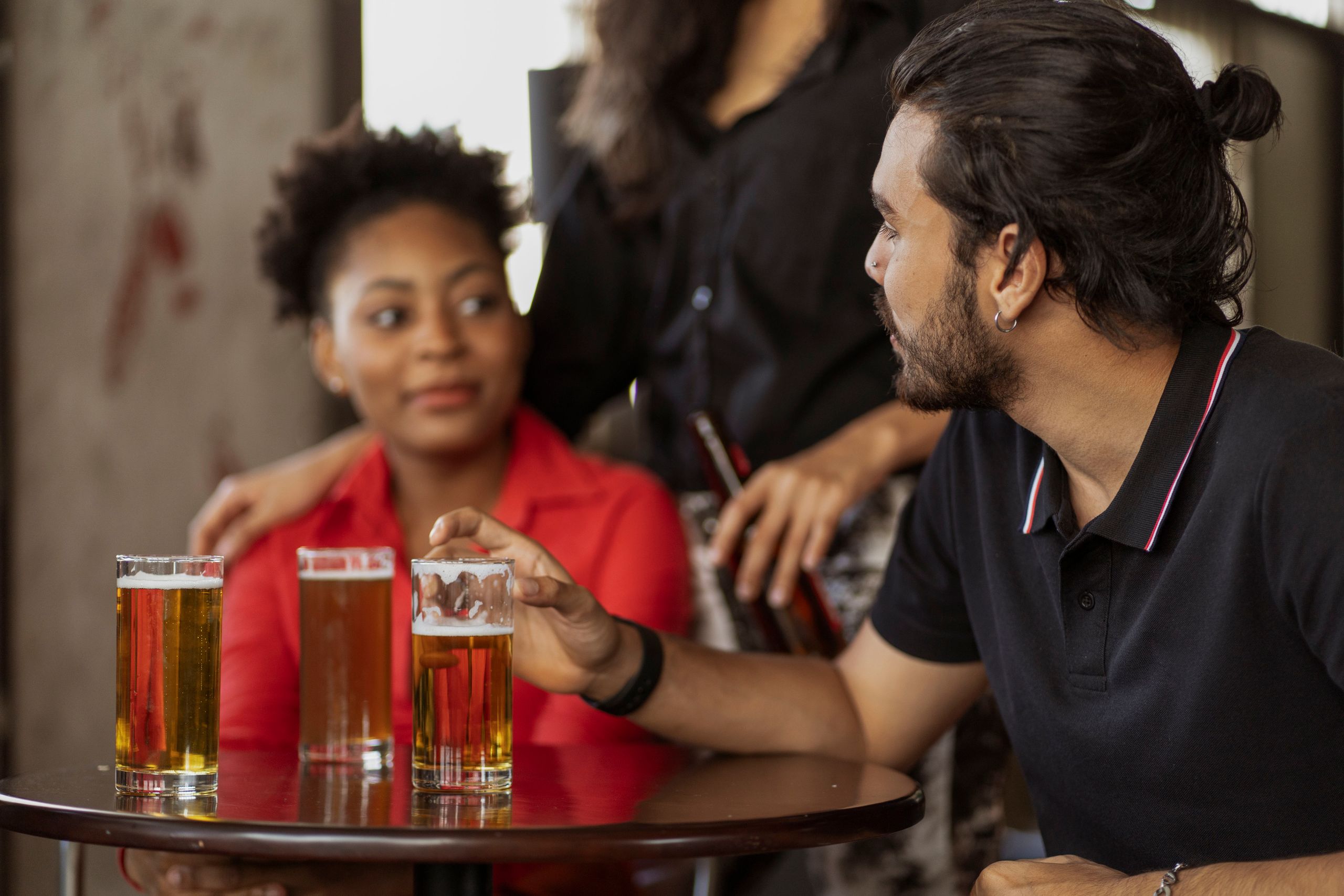 Diverse group of friends enjoying drinks and conversation indoors.
