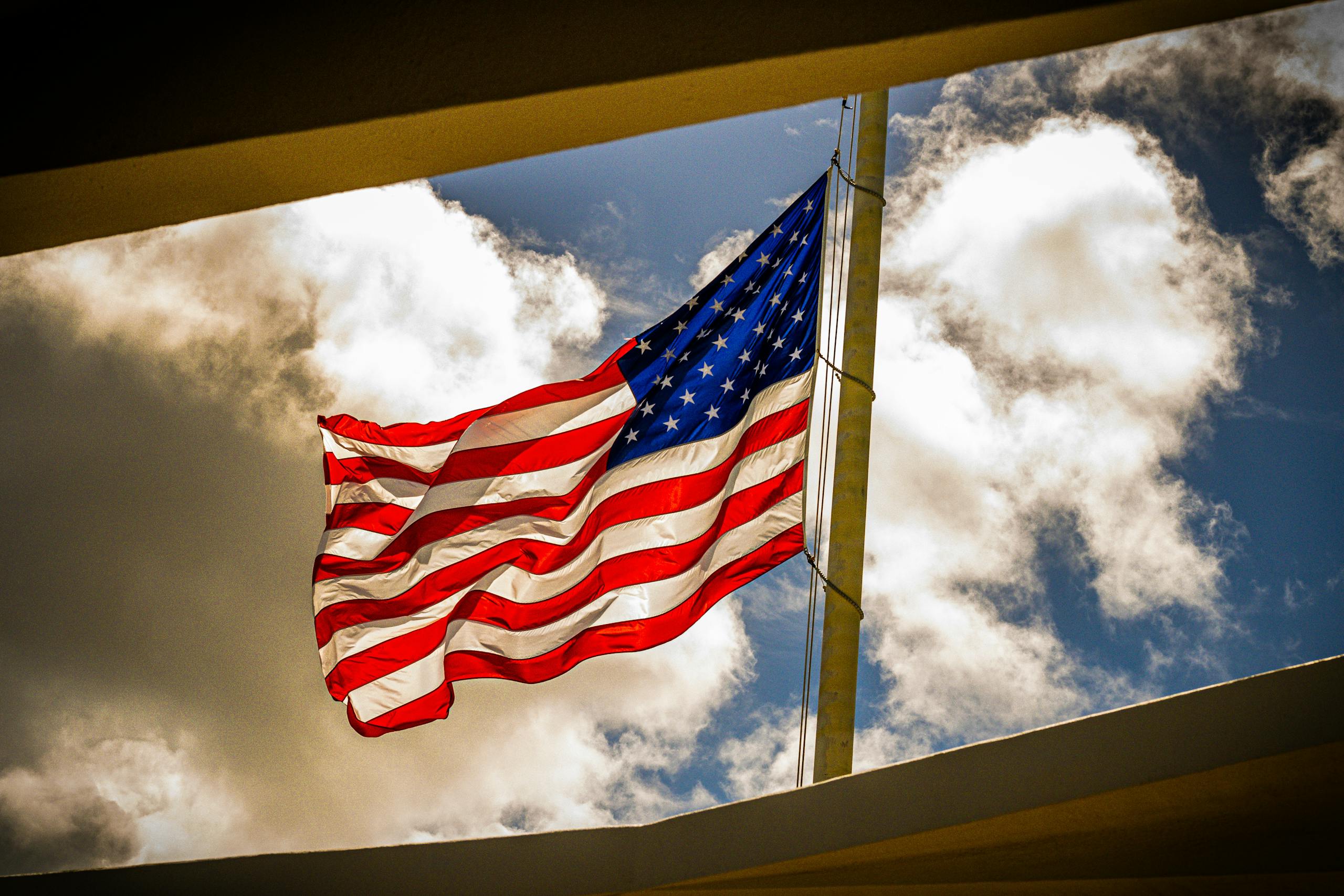 Dramatic view of the American flag waving on a bright day with clouds.