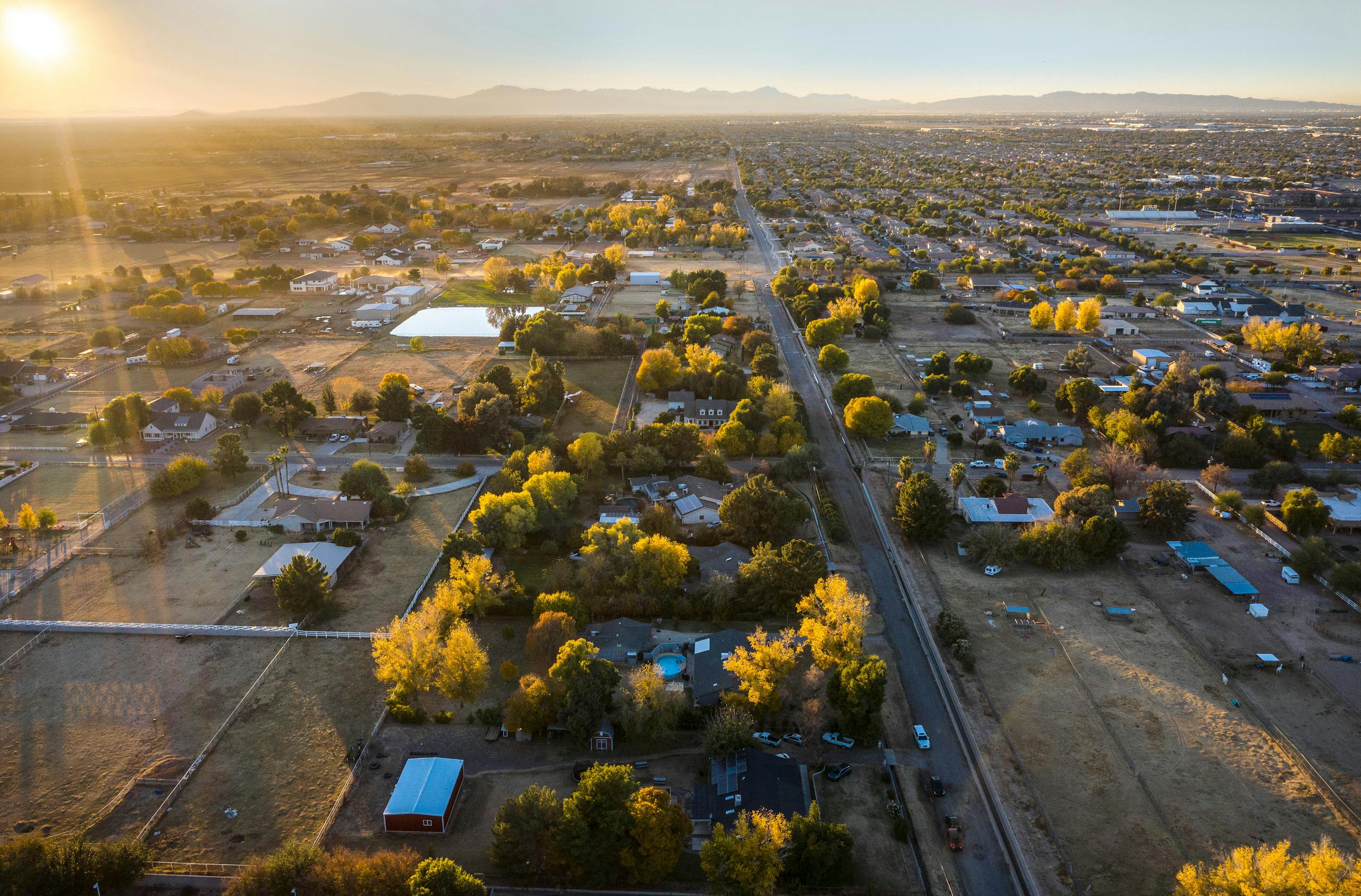 Drone shot capturing a serene rural landscape during a golden sunset, showcasing autumn colors.