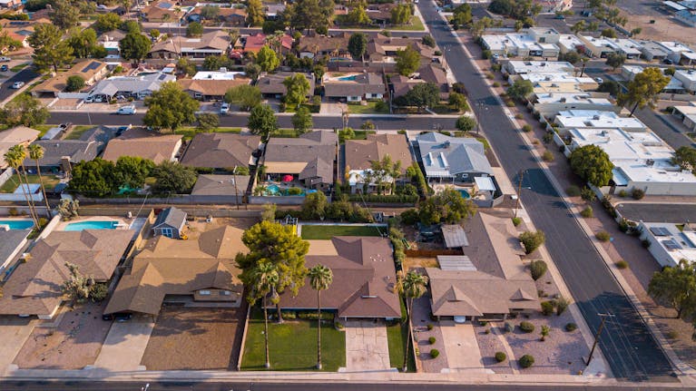 Drone shot of a suburban neighborhood showcasing houses, roads, and lush greenery.