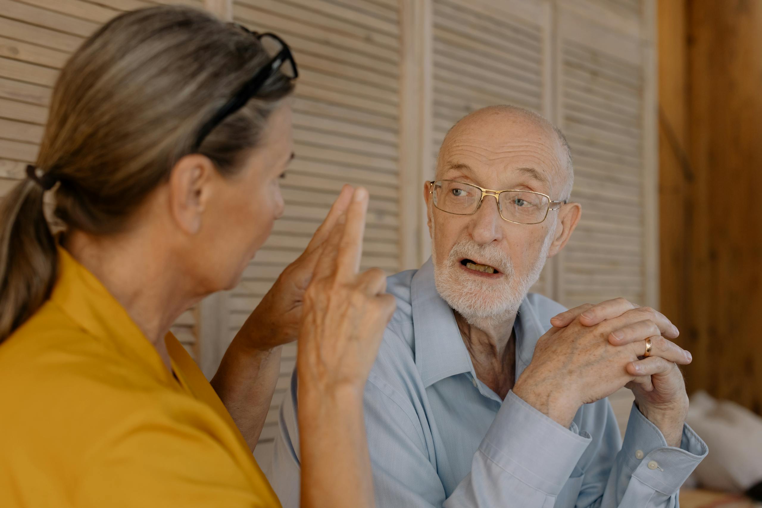 Elderly couple having an engaging conversation indoors, showcasing connection and emotion.