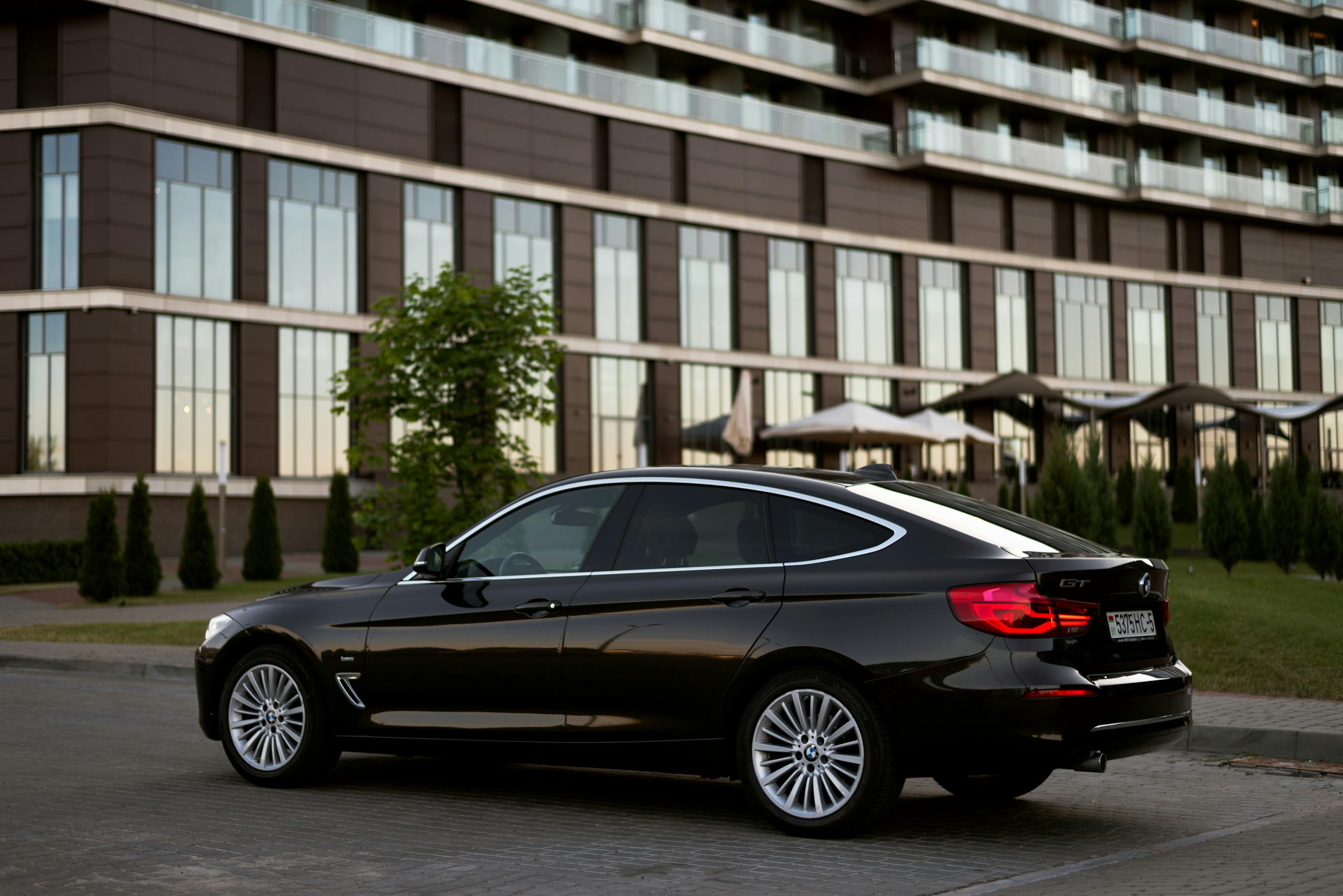 Elegant black sedan parked in front of a modern building in Minsk at twilight.