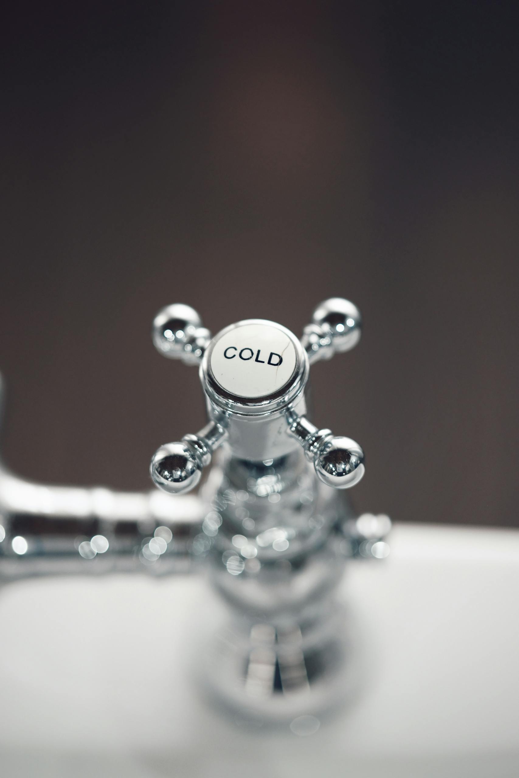 Elegant close-up of a chrome bathroom faucet with a cold water handle, offering a modern touch.