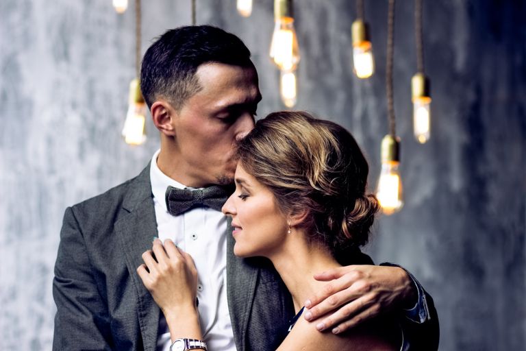 Elegant couple sharing an intimate moment under glowing vintage hanging lights.