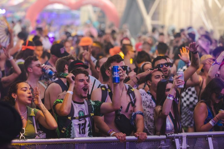 Energetic crowd at a music festival enjoying live performances with drinks.