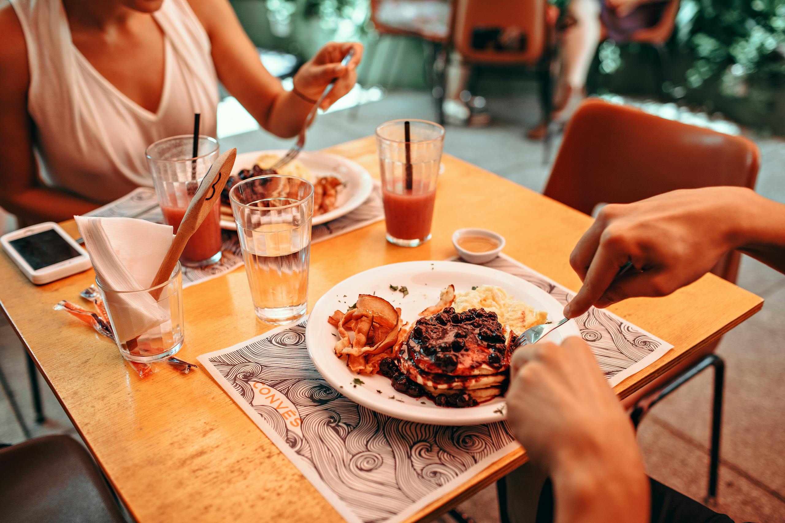 Enjoy a cozy outdoor breakfast with pancakes and fresh juice in a relaxed setting.