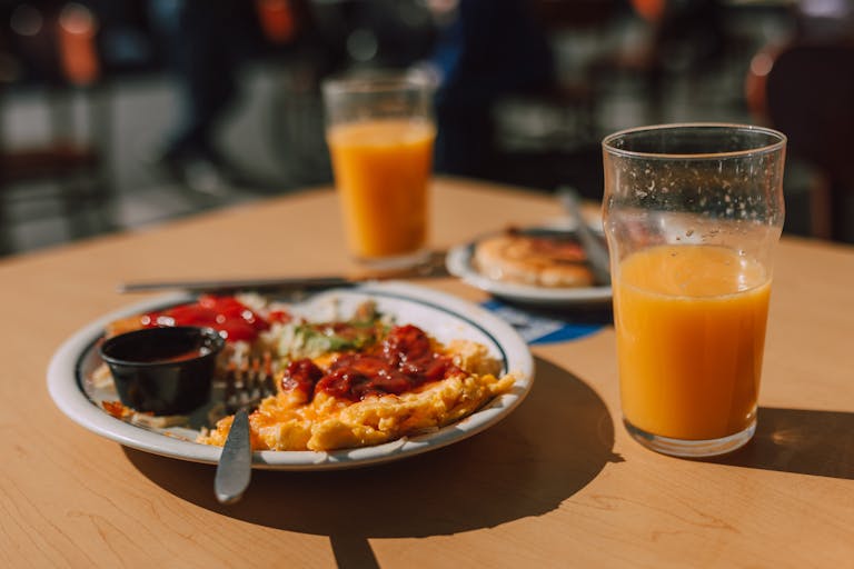 Enjoy a delicious breakfast featuring an omelette and fresh orange juice on a sunny day.