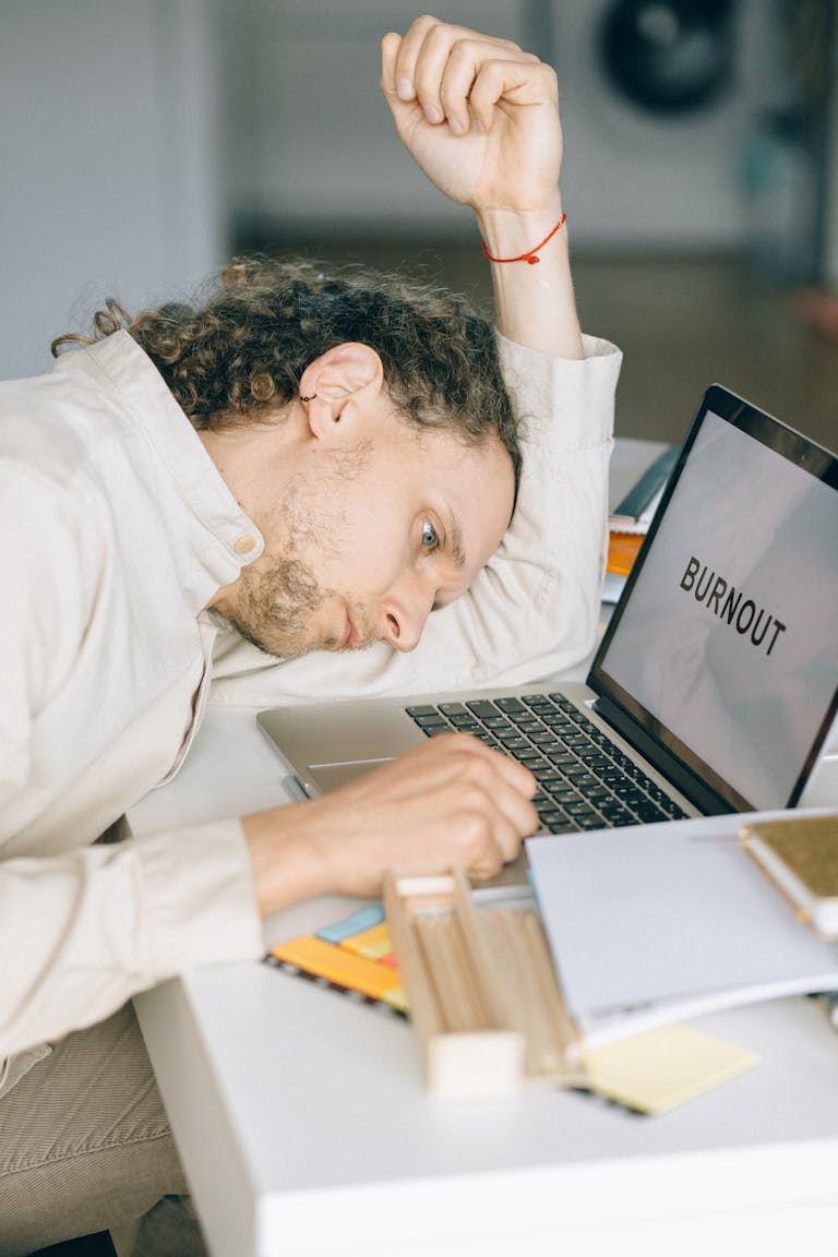 Exhausted employee with head on desk, facing workplace burnout stress.