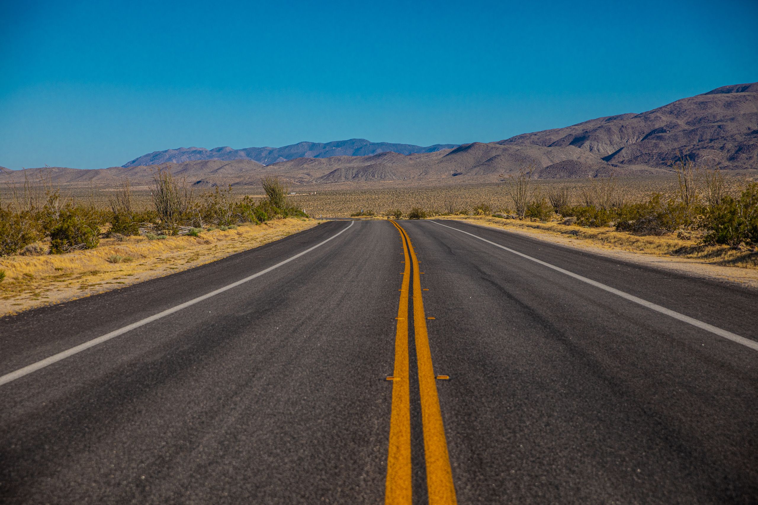 Explore the vast desert landscape along an open highway under a bright blue sky.