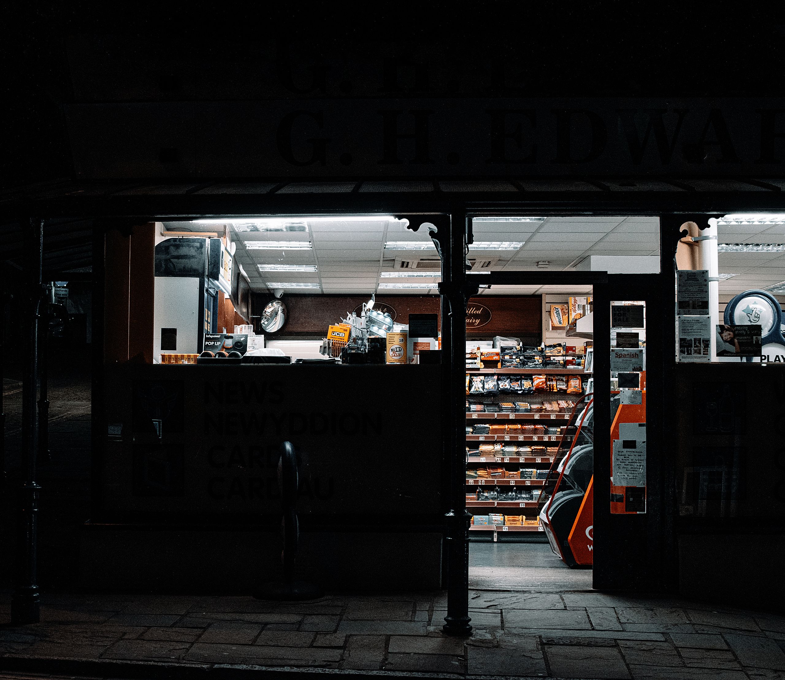 Exterior view of a convenience store at night, showcasing its well-lit interior.