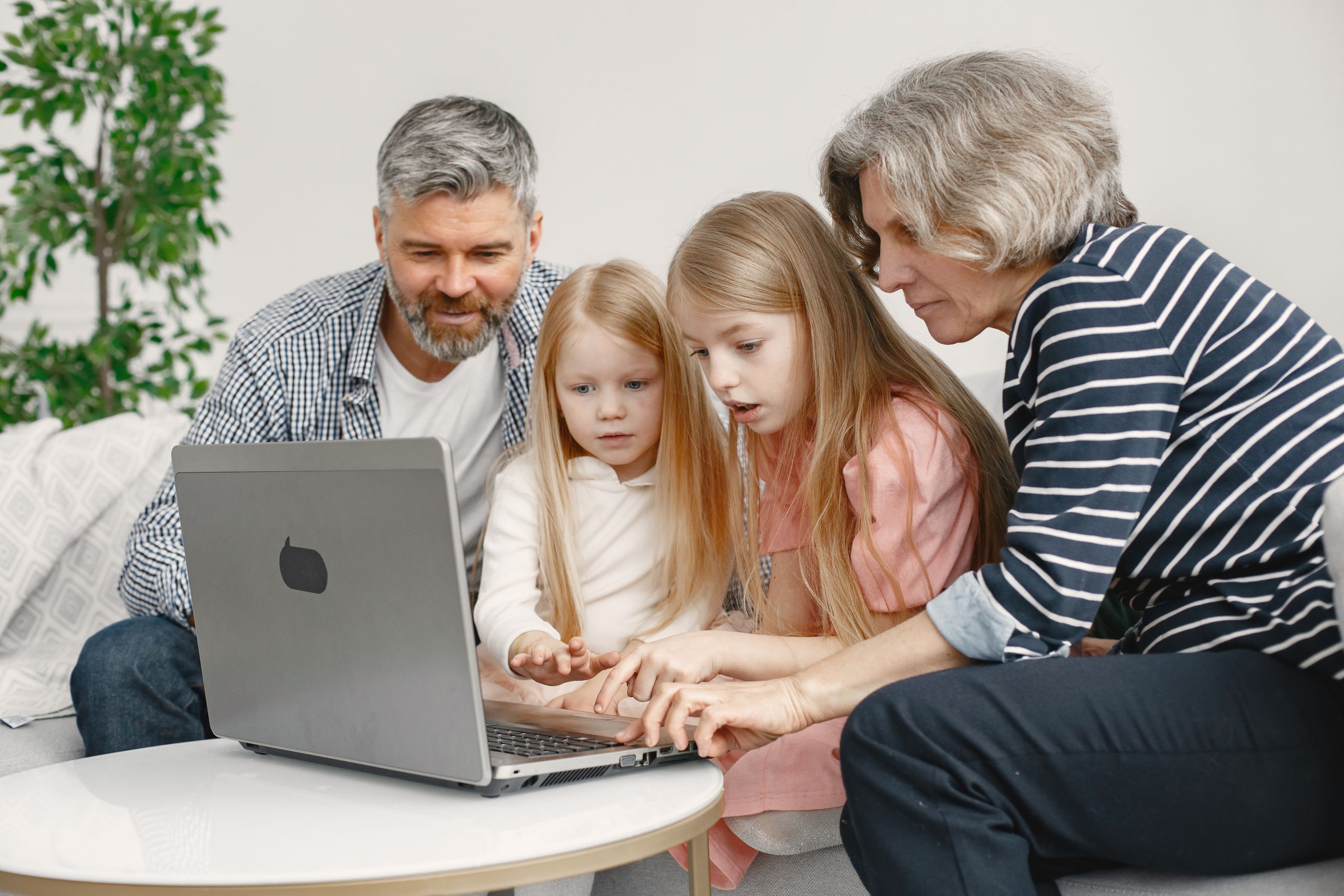 Family members of different ages enjoy quality time together while browsing on a laptop.