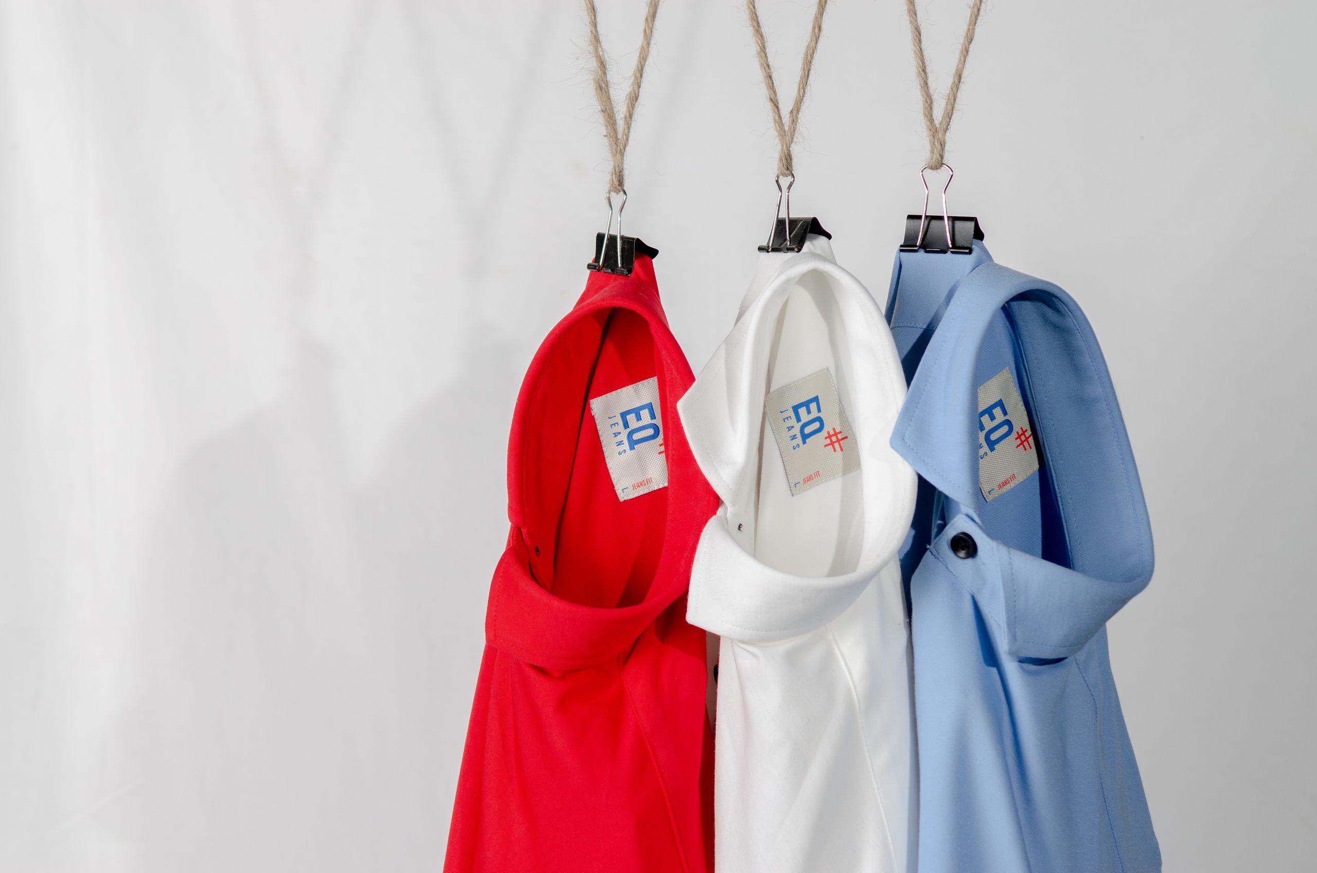Fashionable red, white, and blue shirts hanging neatly on a white background.