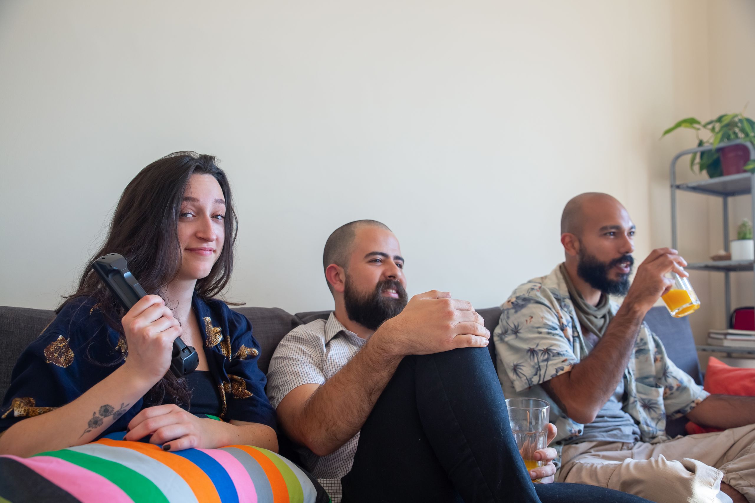 Friends enjoying a relaxed afternoon indoors playing games and sipping drinks on a cozy sofa.