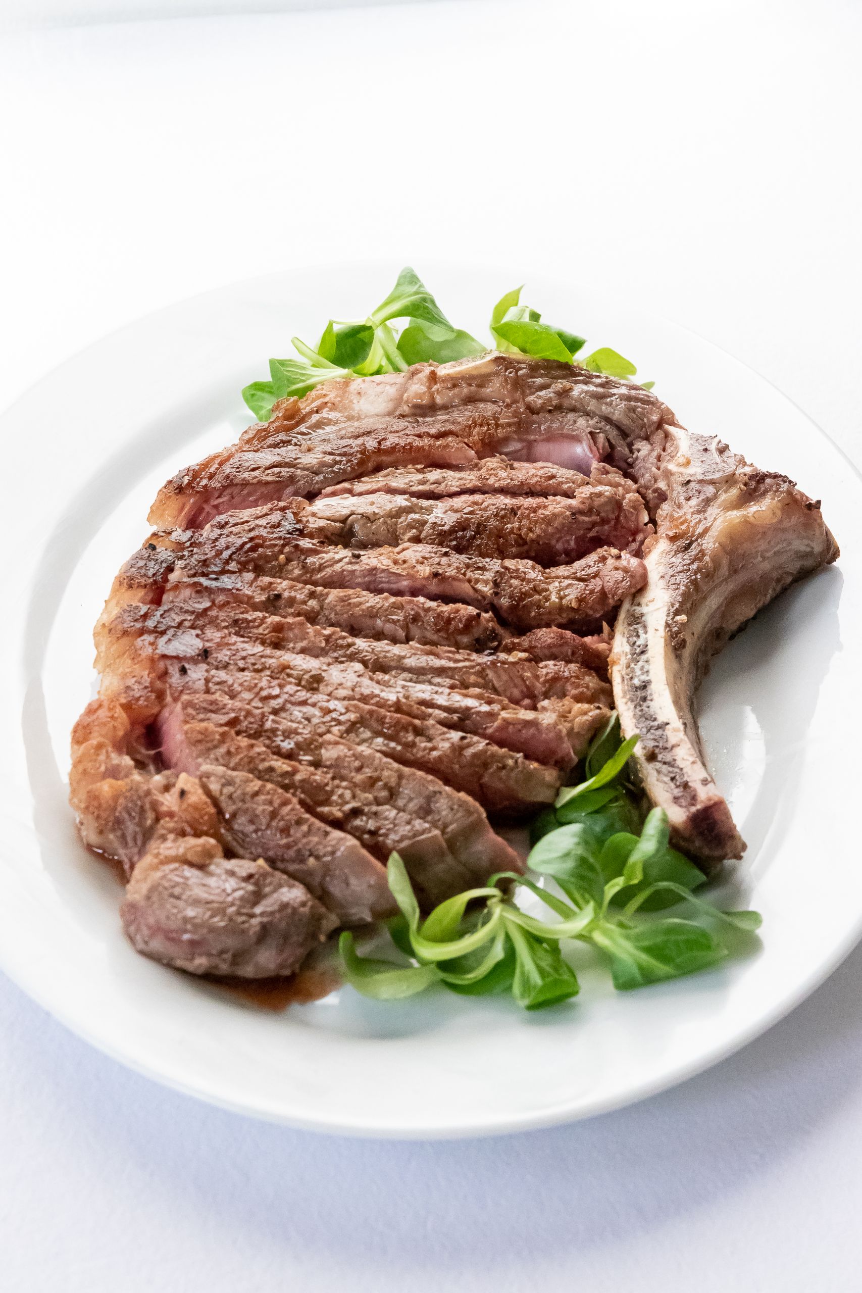 From above delicious medium rare ribeye steak on salad leaves served in light restaurant